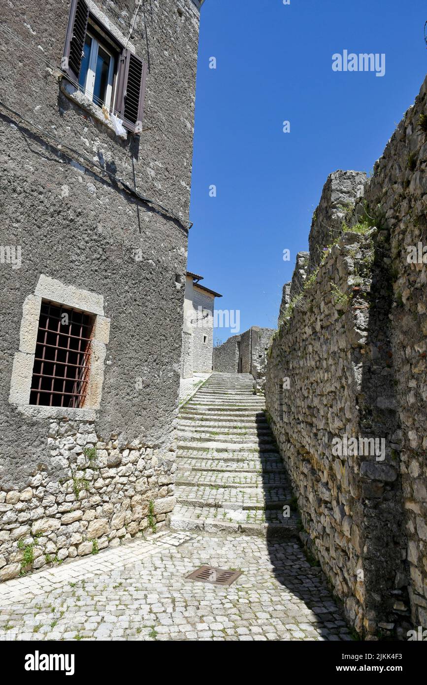 A vertical shot of a street between old medieval stone buildings in Italy. Stock Photo