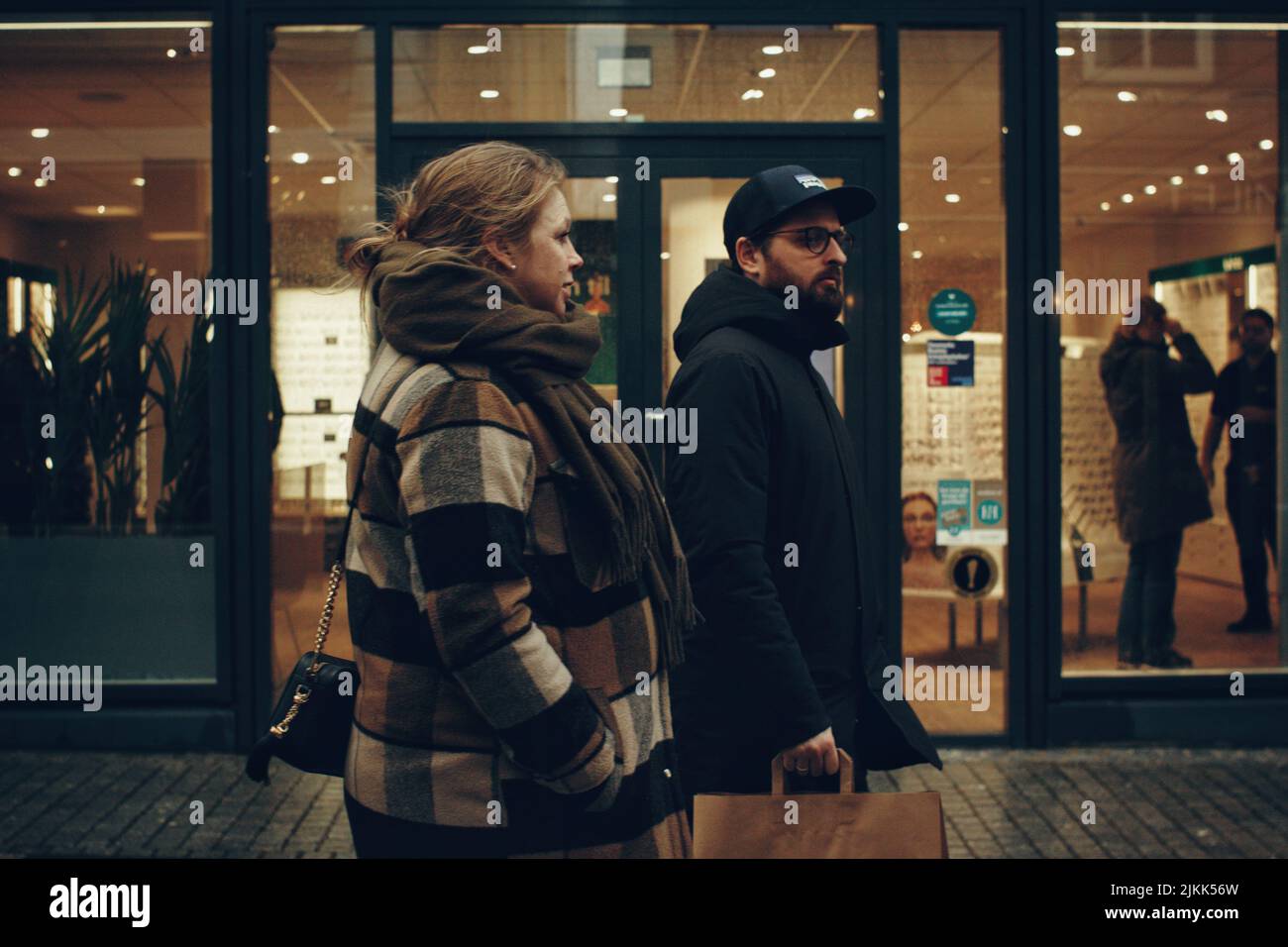 A closeup of man and woman passing by the store. Holstebro,  Denmark. Stock Photo
