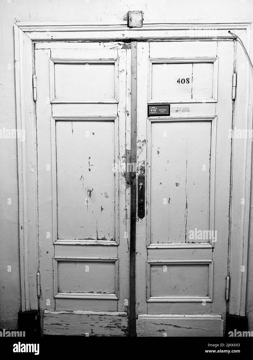 A vertical black and white shot of an old door with number '408' written on it Stock Photo