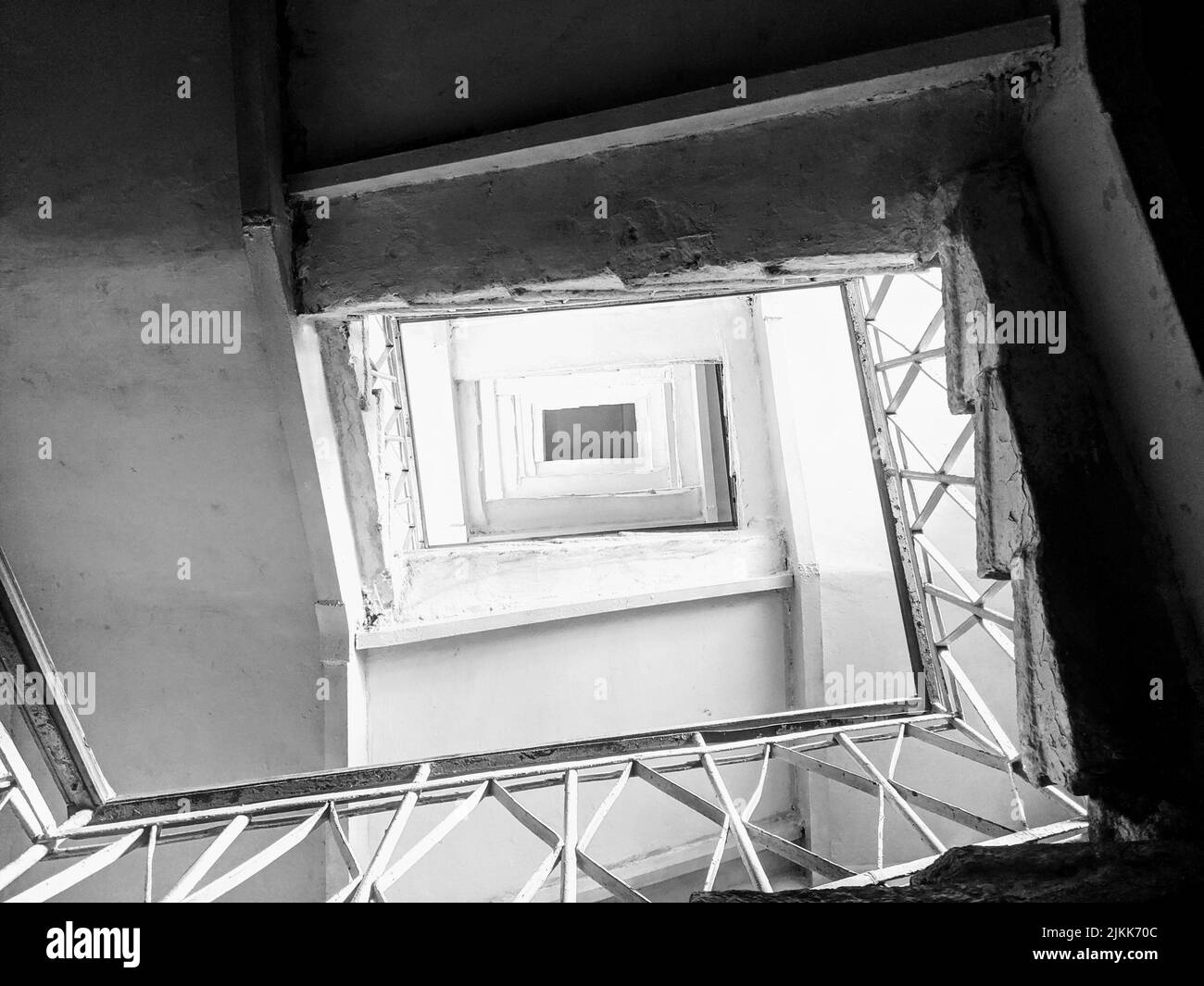 An overhead shot of a staircase on all floors of a building in grayscale Stock Photo