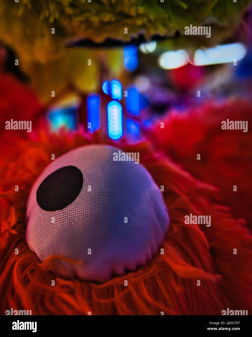 A closeup of an eye of a red, hairy stuffed toy Stock Photo