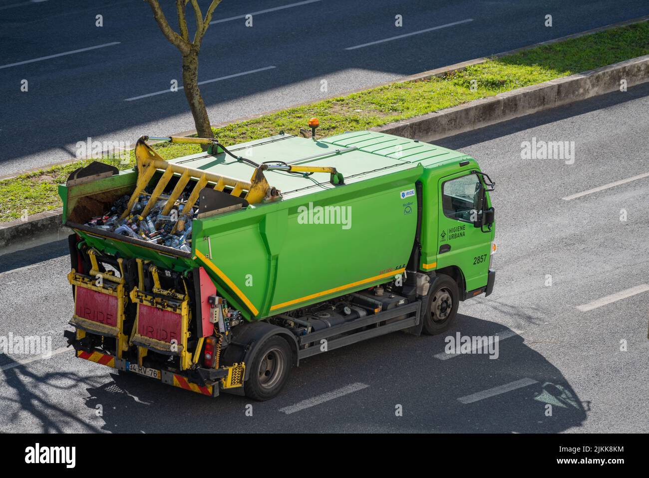 A green truck for glass and waste collection and recycling driving in