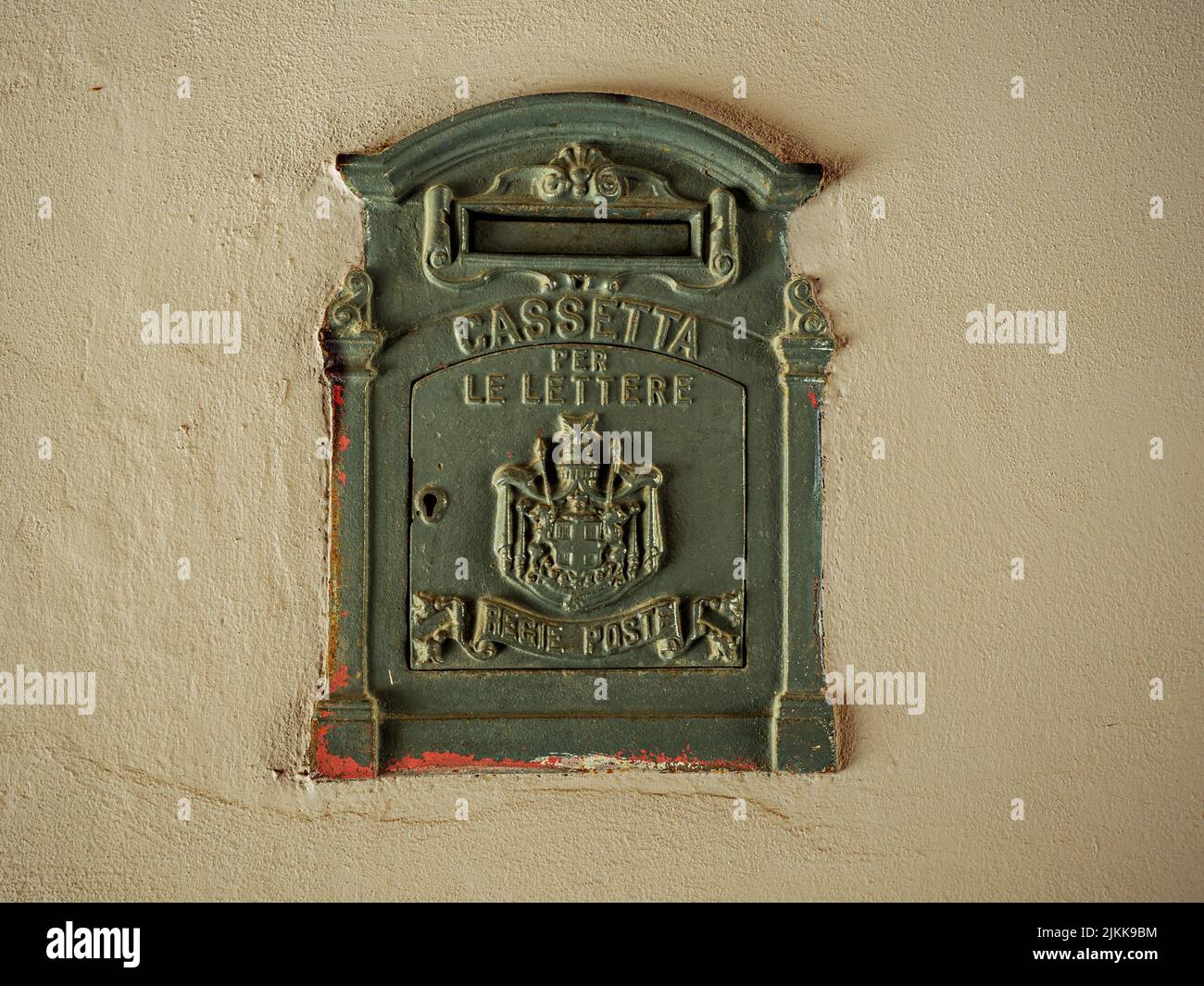 Antique  mailbox with rust marks built-in the white wall of an old building.Inscription says: mailbox, royal postal system. Stock Photo