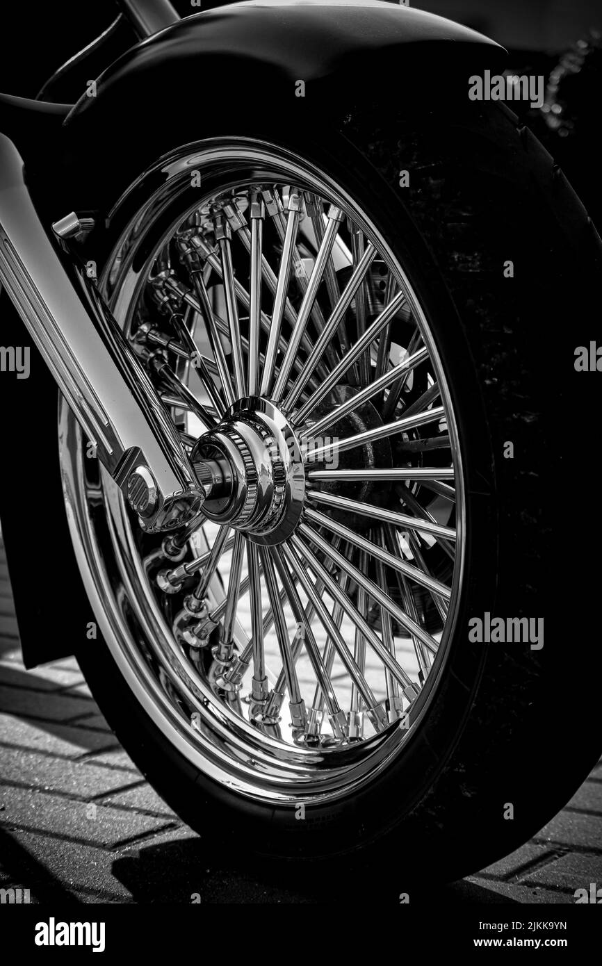 A closeup grayscale shot of a shiny motorcycle tire on a tile pavement