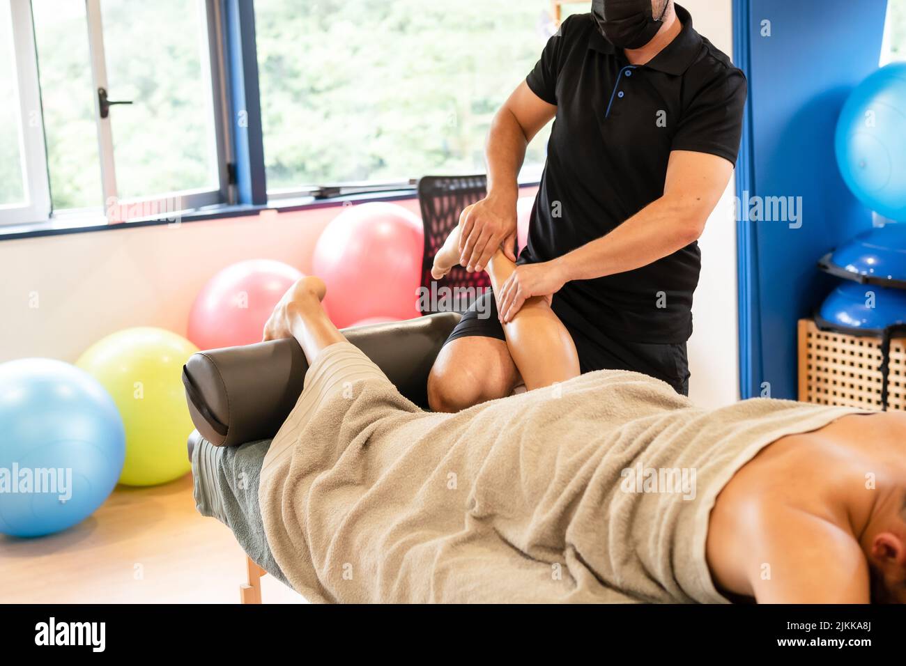 Detail of therapeutic leg massage and sports recovery osteopathy. A sporty man receiving a massage by a physiotherapist on a massage table Stock Photo