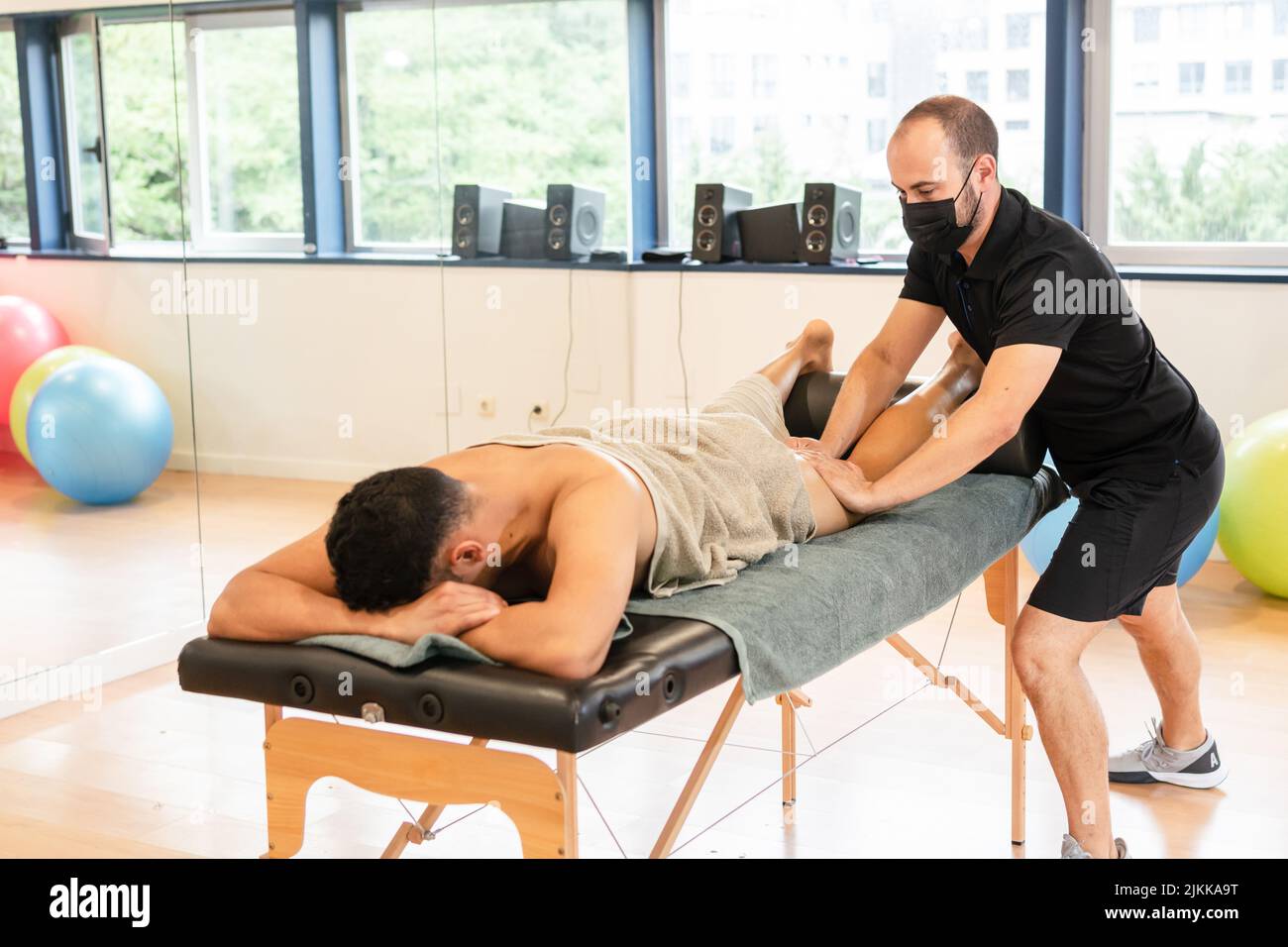 Therapeutic leg massage and sports recovery osteopathy. A sporty man receiving a massage by a physiotherapist on a massage table Stock Photo