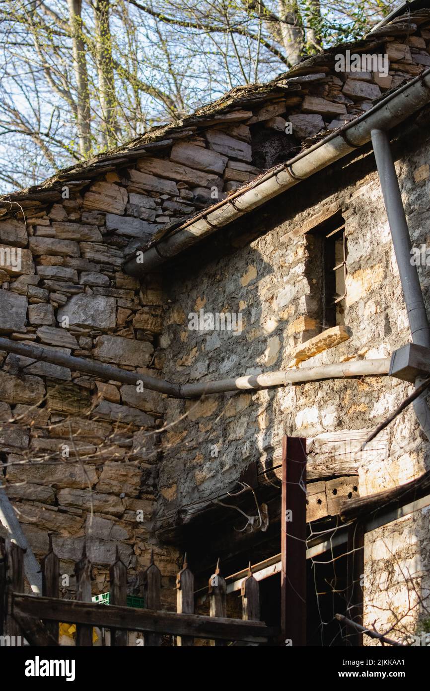 A low angle shot of a part of old rustic house under the trees on sunny day Stock Photo