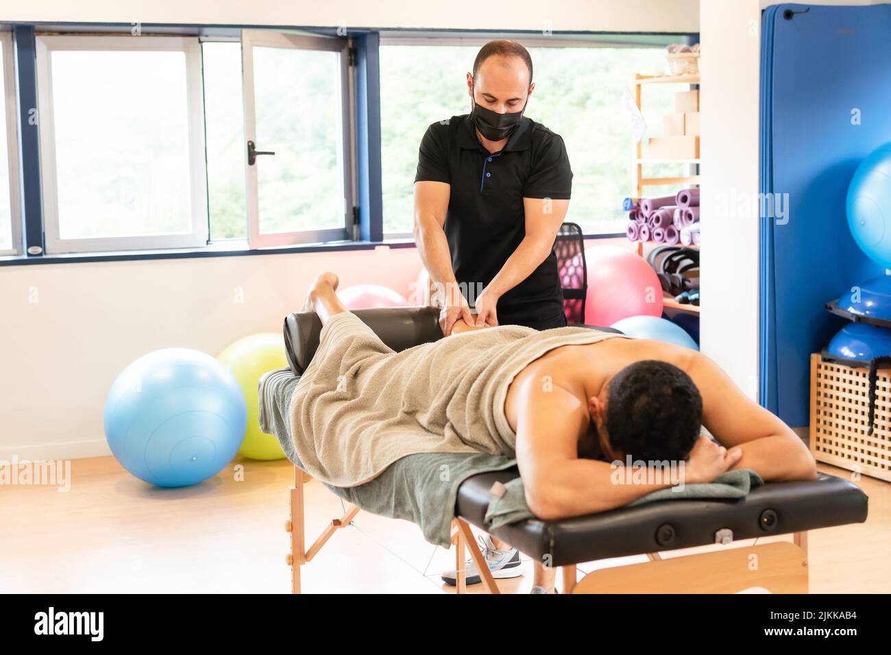 Therapeutic leg massage and sports recovery osteopathy. A sporty man receiving a massage by a physiotherapist on a massage table Stock Photo