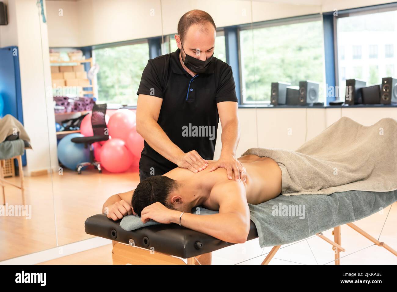 An athletic man receiving a recovery massage by a physiotherapist on a stretcher Stock Photo