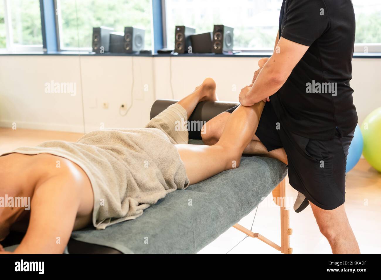 Detail of therapeutic leg massage and sports recovery osteopathy. A sporty man receiving a massage by a physiotherapist on a massage table Stock Photo