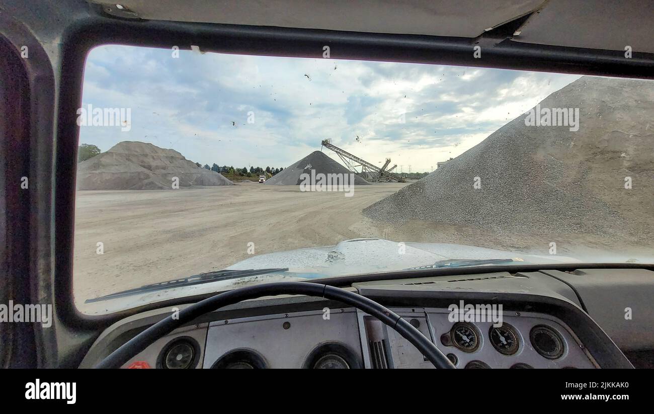 A point of view shot from the driver's side of an old truck at a query driving to pick up gravel Stock Photo