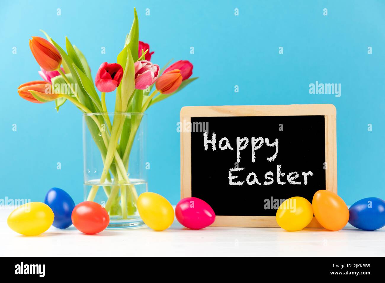 colorful tulips with chalkboard and easter eggs on a blue background ...
