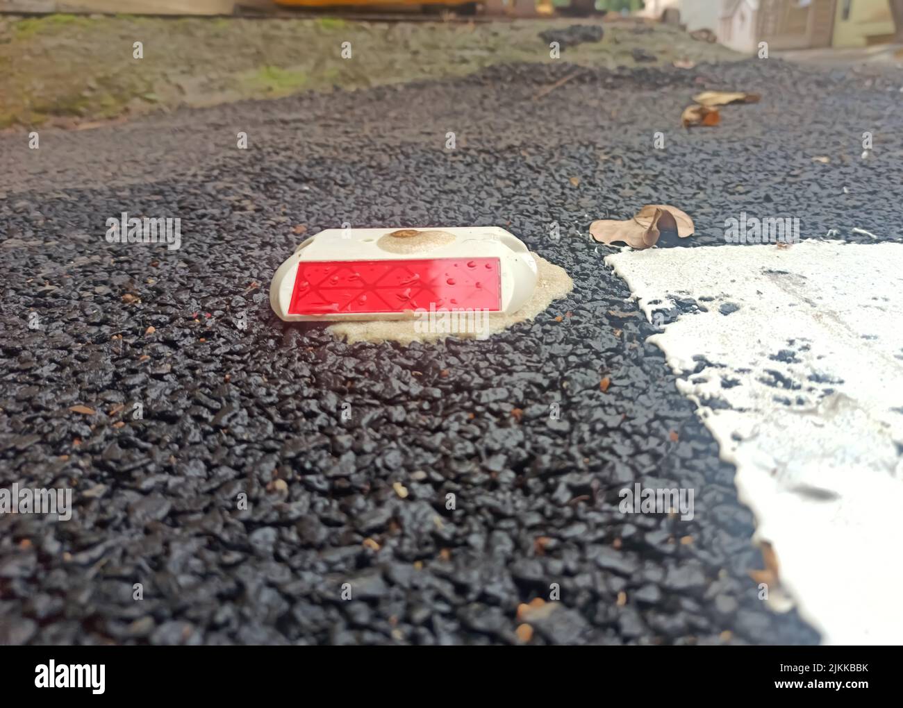 A Selective focus Picture of a Road Reflector installed on Road In India. Road Reflectors guide the Vehicles in dark and avoid accidents. Stock Photo