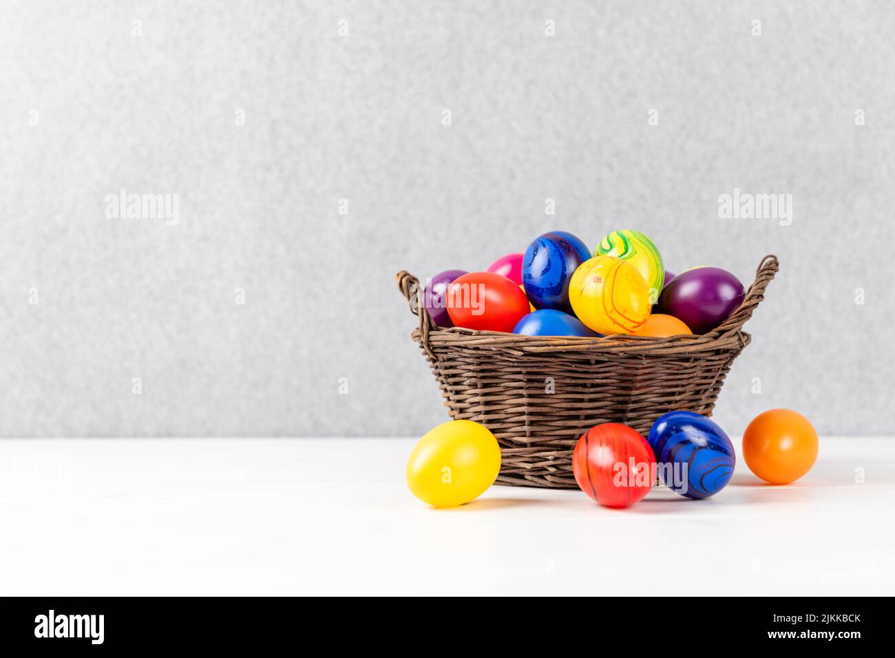 colorful easter eggs in a basket with gray background and copyspace Stock Photo