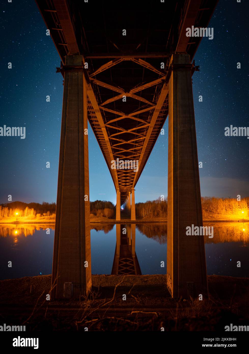 A vertical shot of the Rendsburg High Bridge in the night with beautiful lights on a river in Germany Stock Photo