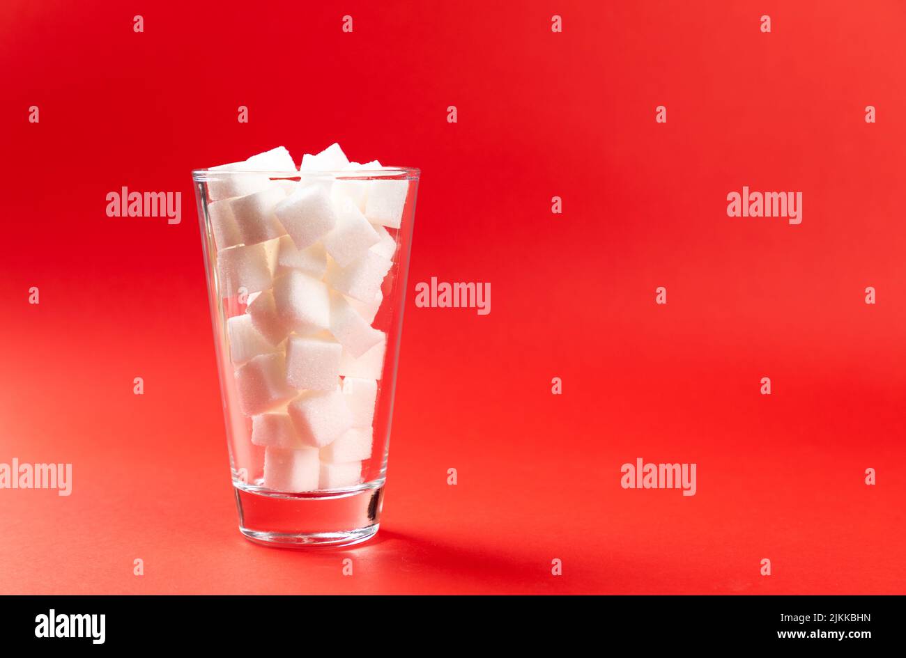 glass with sugar cubes on a red background Stock Photo