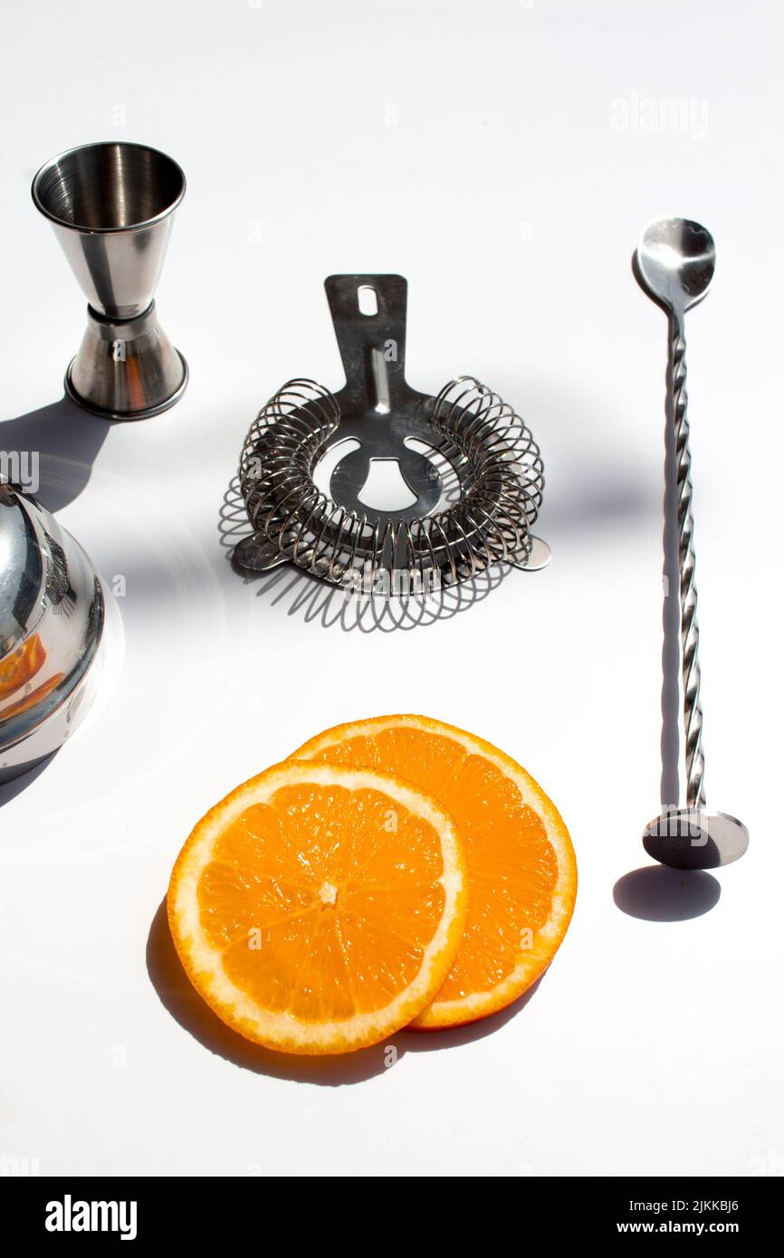 A vertical shot of barware for making cocktails with orange slices on a white background Stock Photo