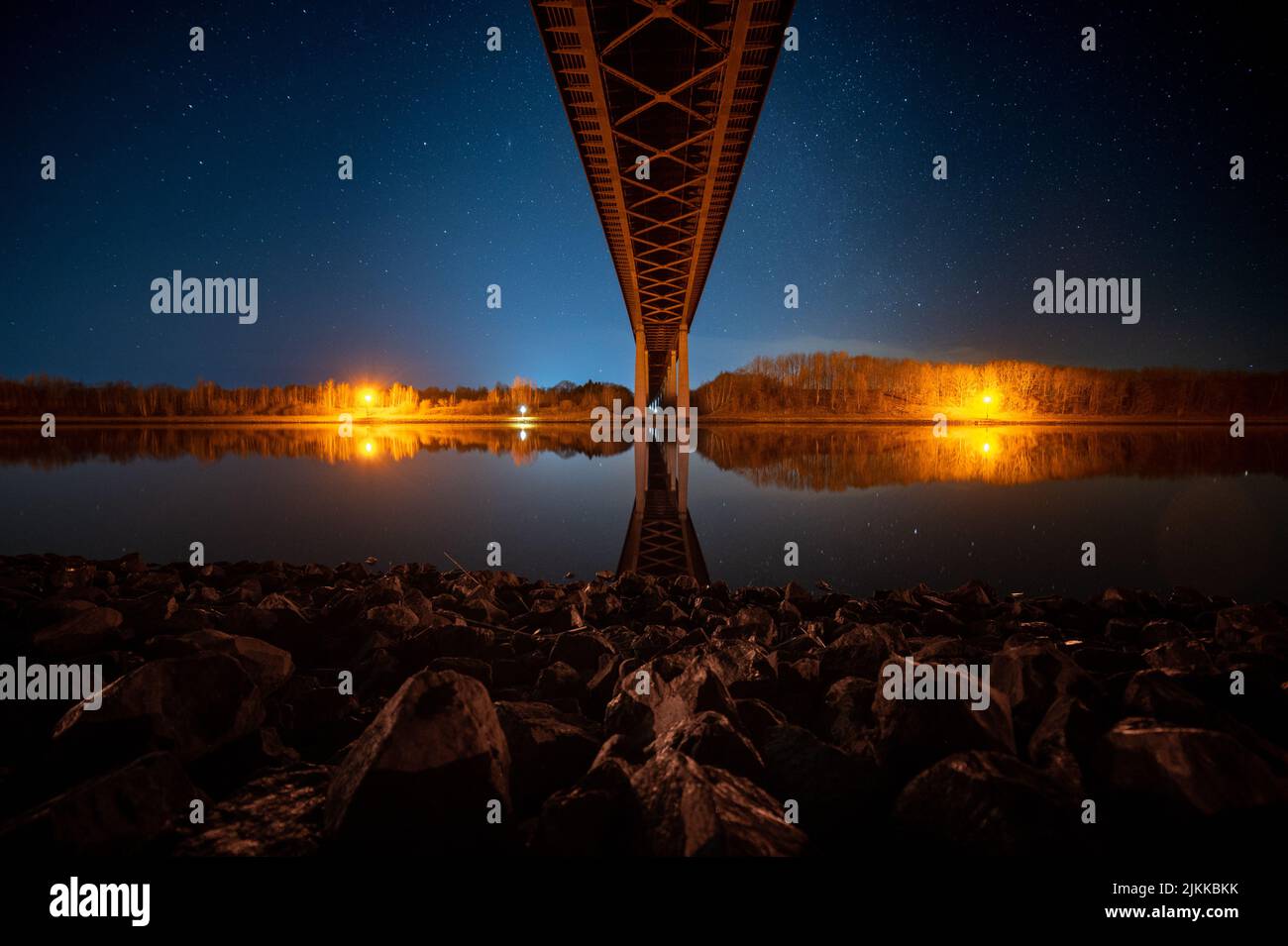 A beautiful shot of Rendsburg High Bridge next to a river and rock beach in the night Stock Photo