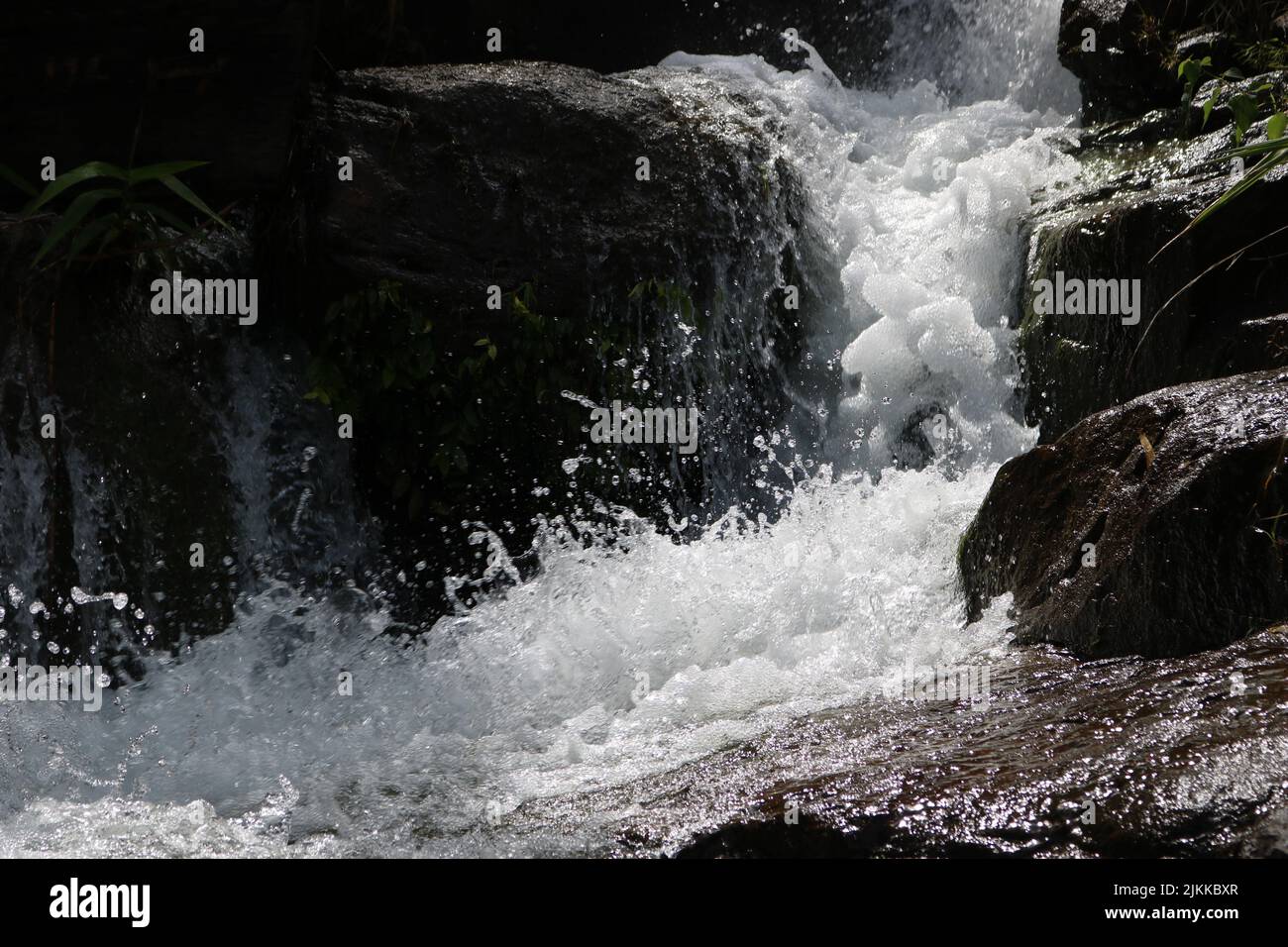 A beautiful shot of a streaming river coming out of in the middle of rocks. Stock Photo