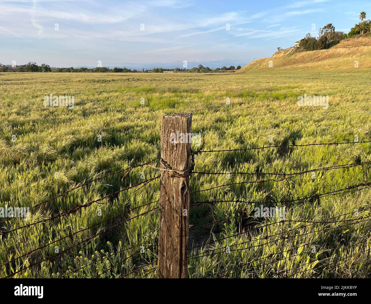 An old fence in an open field in Fresno, California on cloudy sky