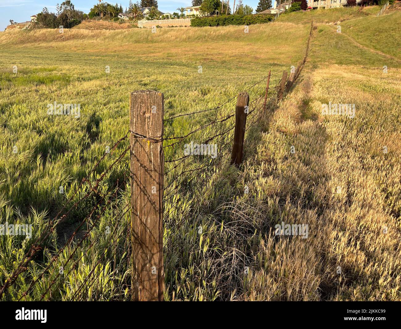 An old fence in an open field in Fresno, California on cloudy sky