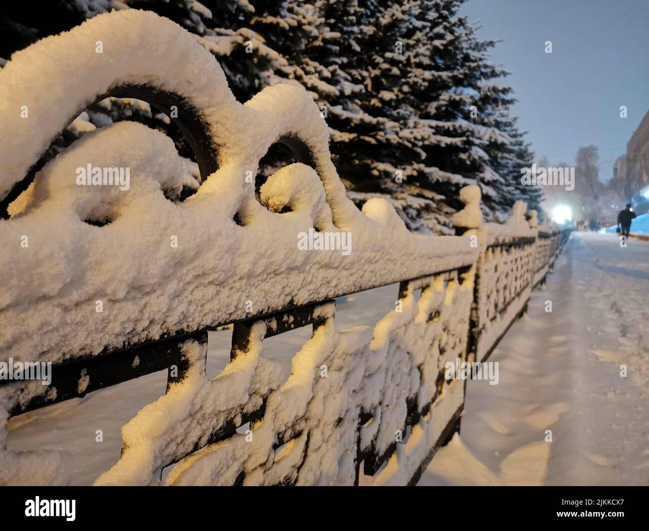 A closeup shot of the metal fence fully covered in snow in the park at ...