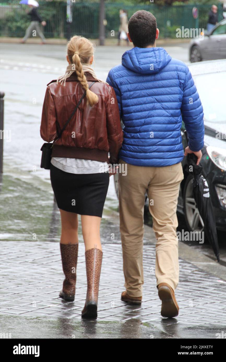 A back view of couple holding hands and walking together in street in ...