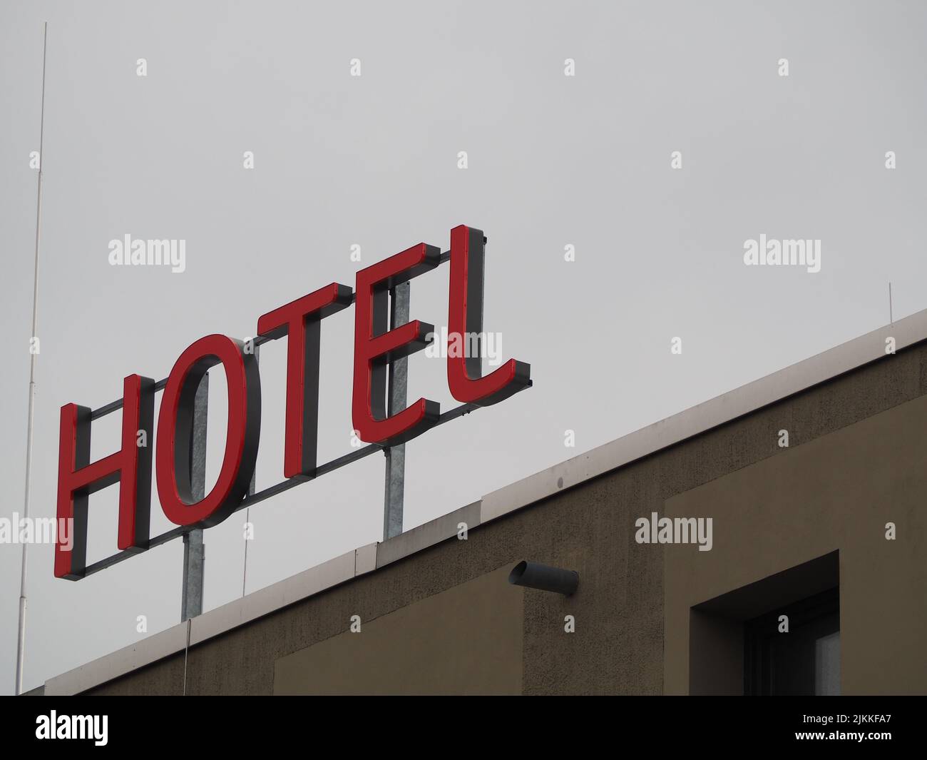 A low angle shot of a red Hotel sign on the top of a building against cloudy sky during daytime Stock Photo