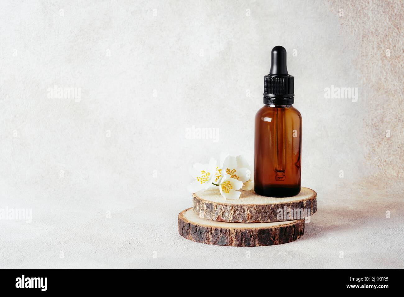 Glass dropper bottles for medical and cosmetic use and jasmine flowers on wooden cut. Natural cosmetic and substantial eco-packaging, SPA concept. Stock Photo