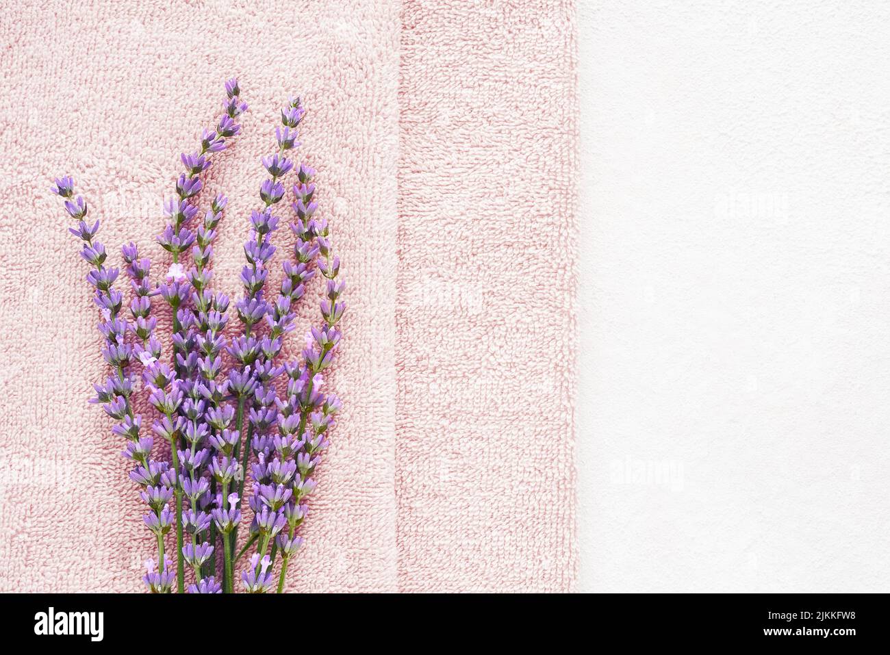 Lavender flowers and pink fluffy towels on the light background. SPA, wellness well-being, body care concept. Copy space for text, top view Stock Photo