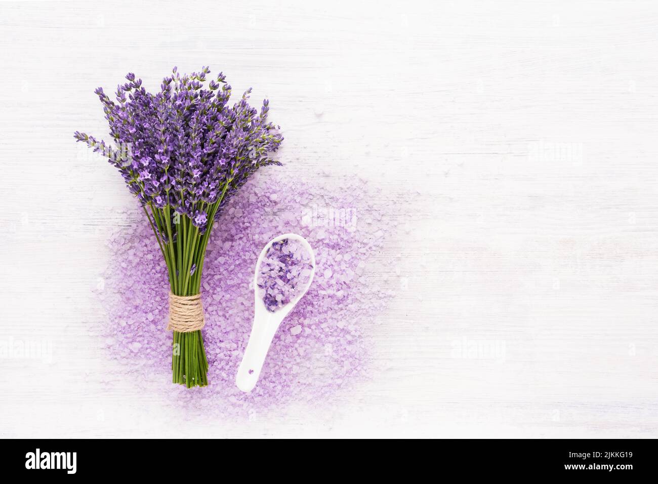 Lavender aroma bath salt and lavender flowers on white wooden background. Spa, skincare concept. Top view, copy space. Selective focus Stock Photo