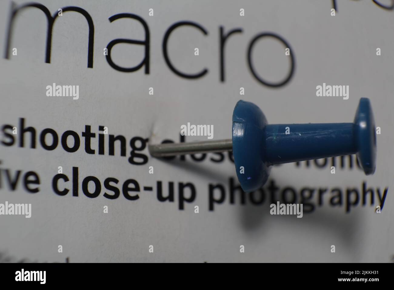 A closeup shot of a blue pushpin on a paper with texts Stock Photo
