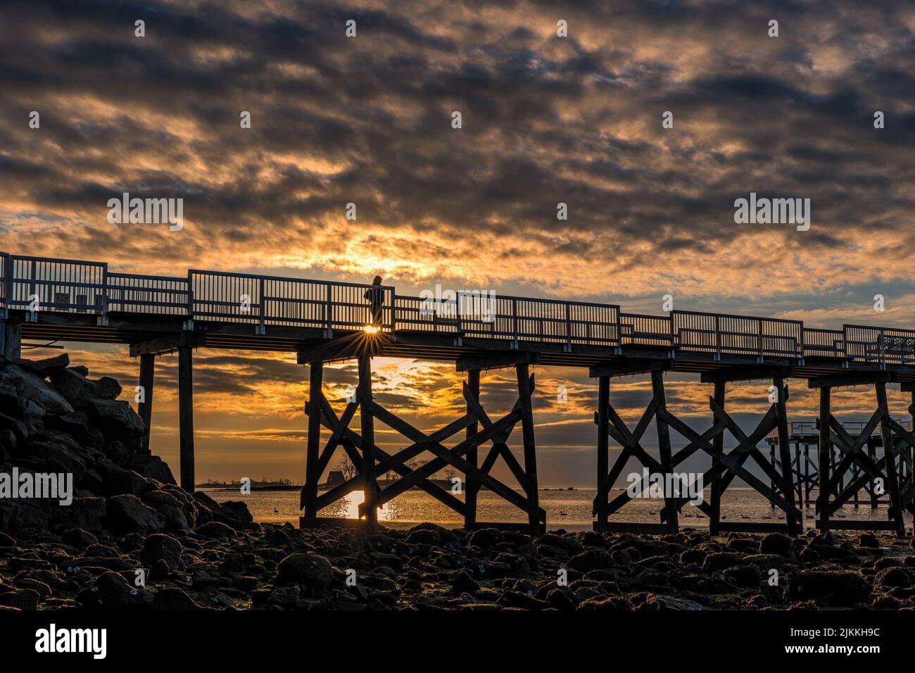 A silhouette of a person walking on a bridge in the background of a ...