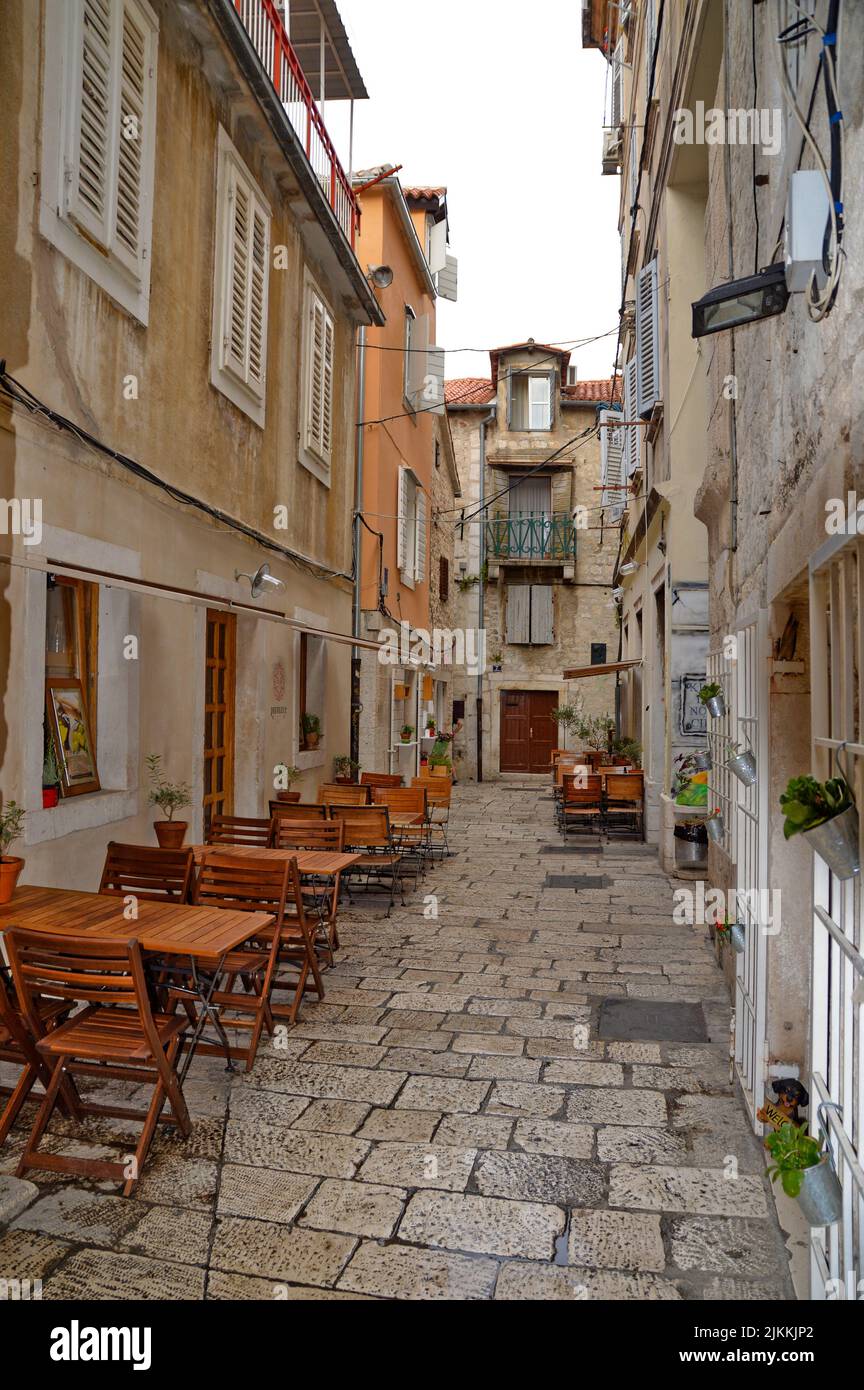 A vertical shot an outdoor cafe in a narrow alley in medieval city of Split in Croatia Stock Photo