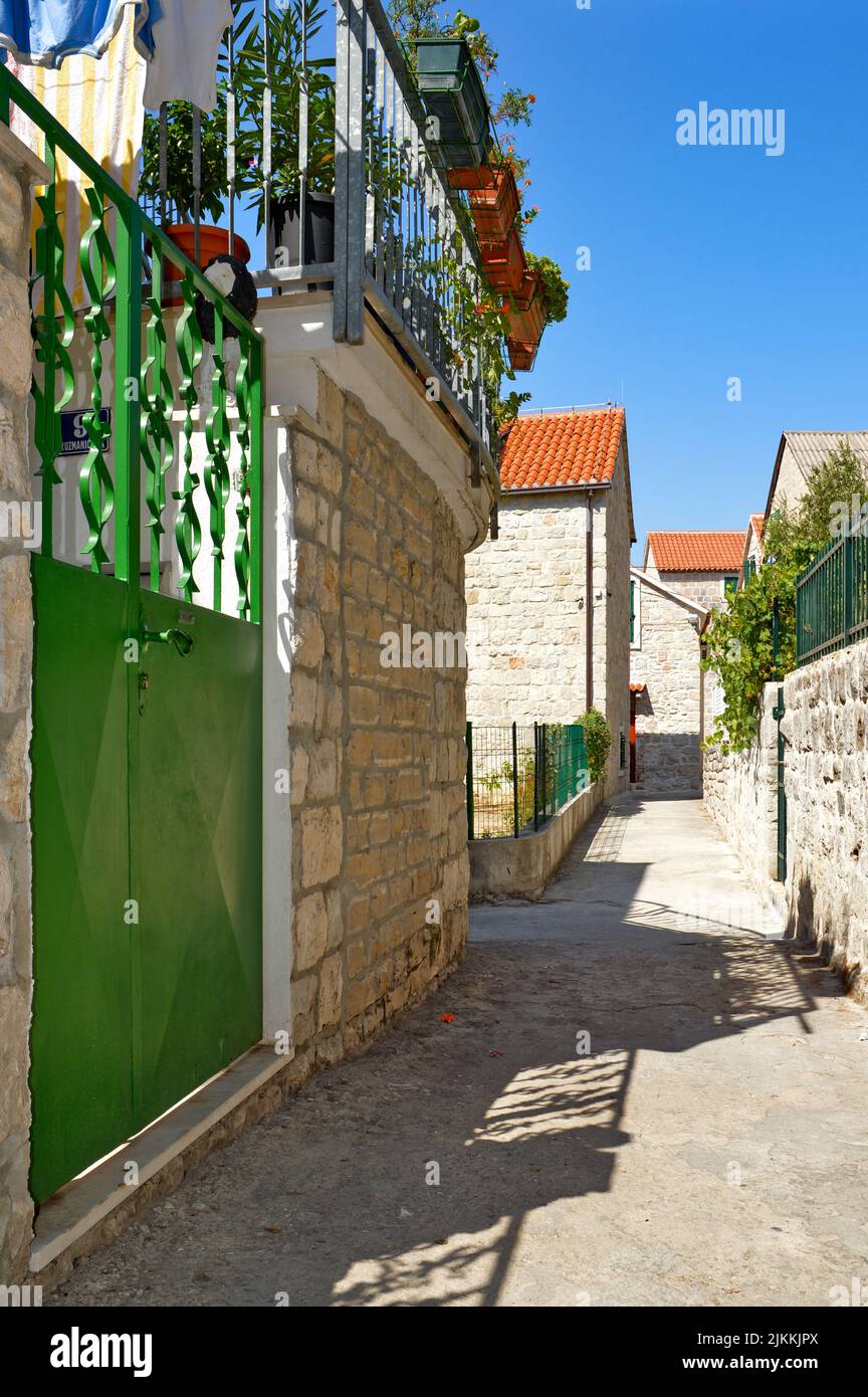 A vertical shot of a cute stone building with green gates on a narrow street in Split, Germany Stock Photo