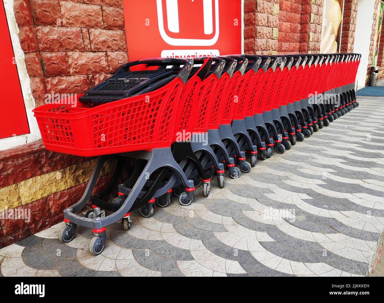 Row of red plastic shopping carts parking in the supermarket. Concept of shopping. Supermarket
