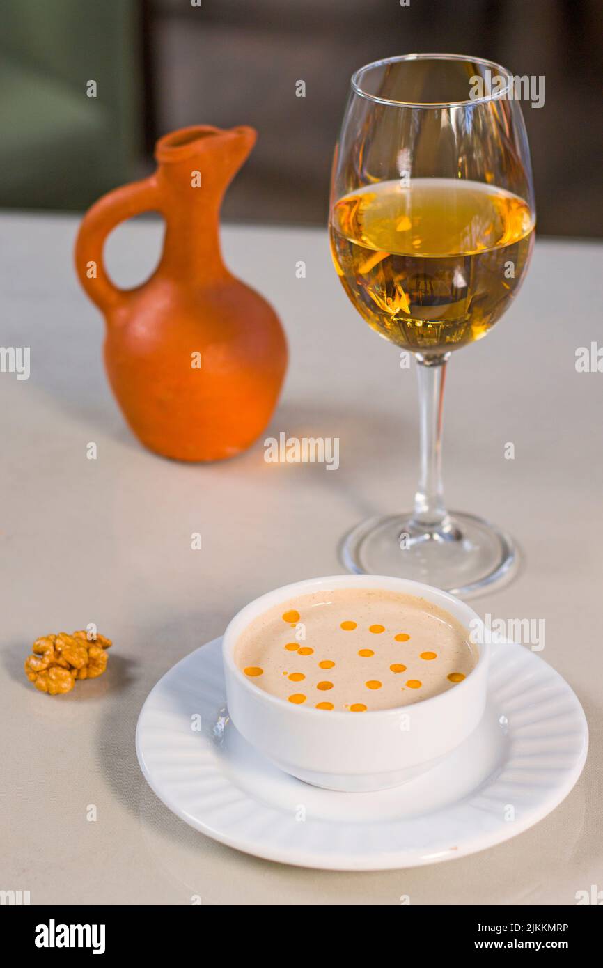 Walnut sauce in the bowl on the table with white wine and walnuts, ready to eat. Stock Photo