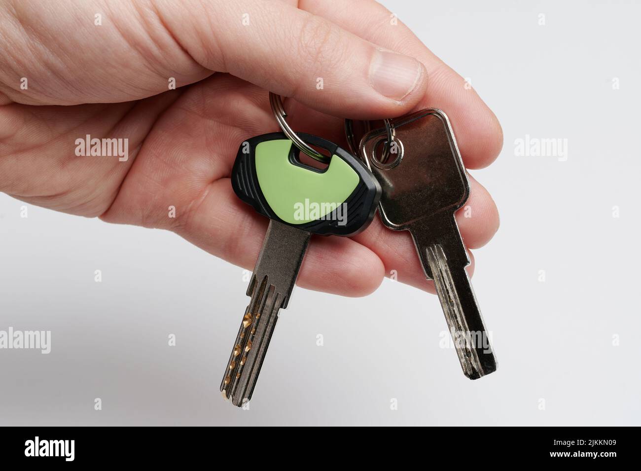 Hand hold metal keys isolated on white studio background Stock Photo