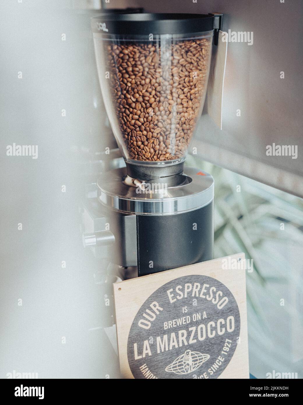A verticale shot of Coffee beans in grinder hopper with wooden sign