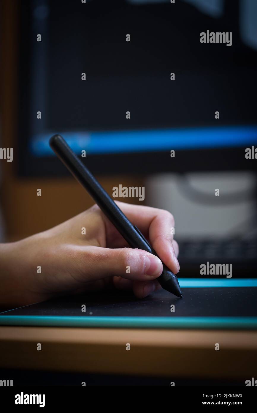 A vertical shot of a hand drawing on a graphic design tablet with a