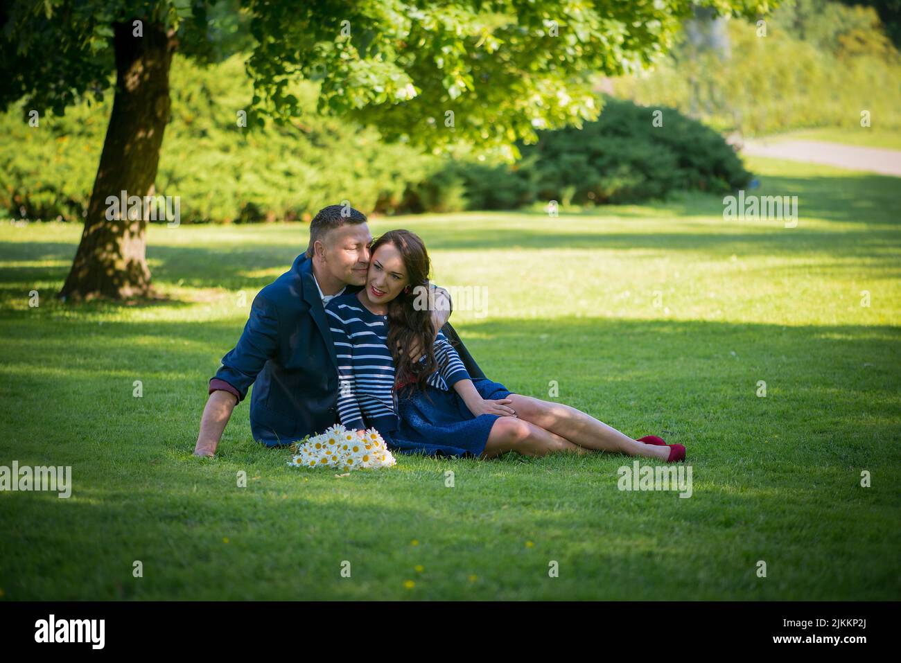 A Latvian couple sitting on the green lawn of a park Stock Photo