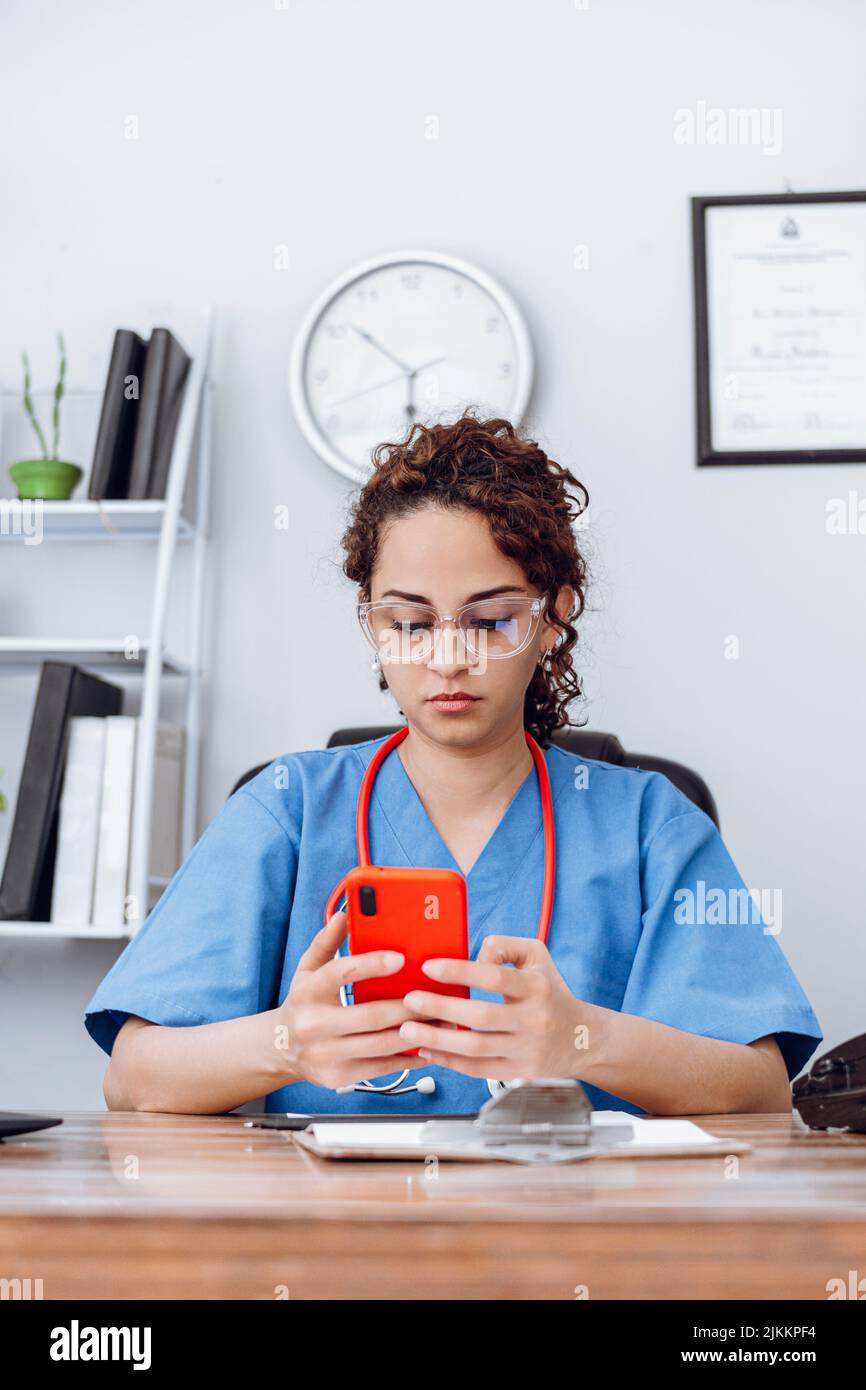 Doctor latin american woman using a mobile phone. Stock Photo