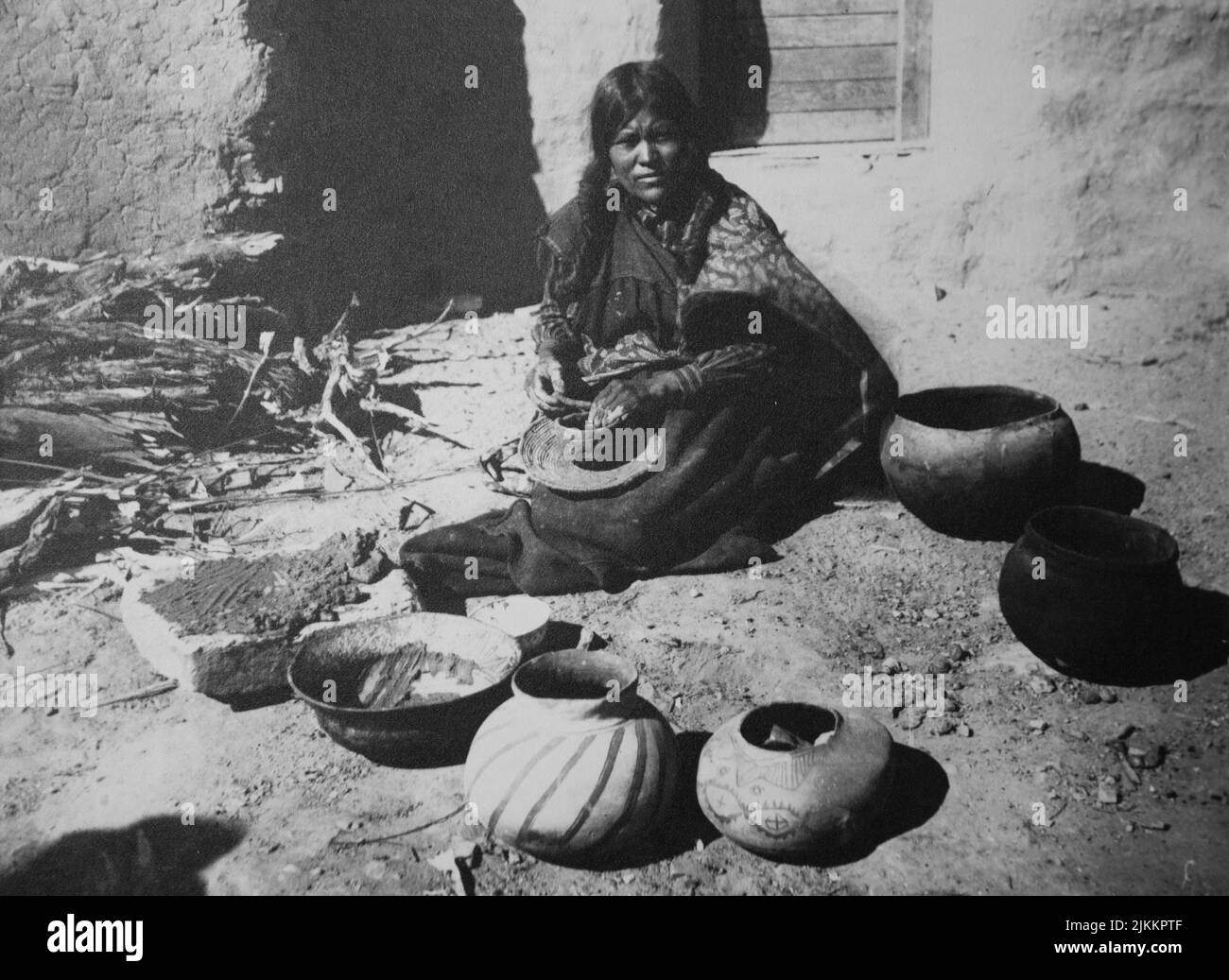 Black and white historical photograph of a Pueblo woman making and selling large traditional pots Stock Photo