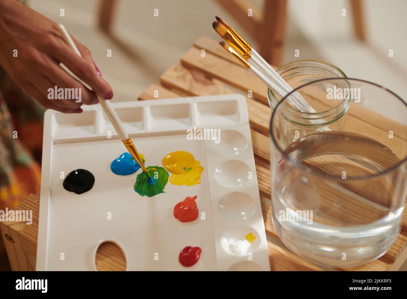 Closeup image of female artist mixing colors on plastic palette Stock Photo