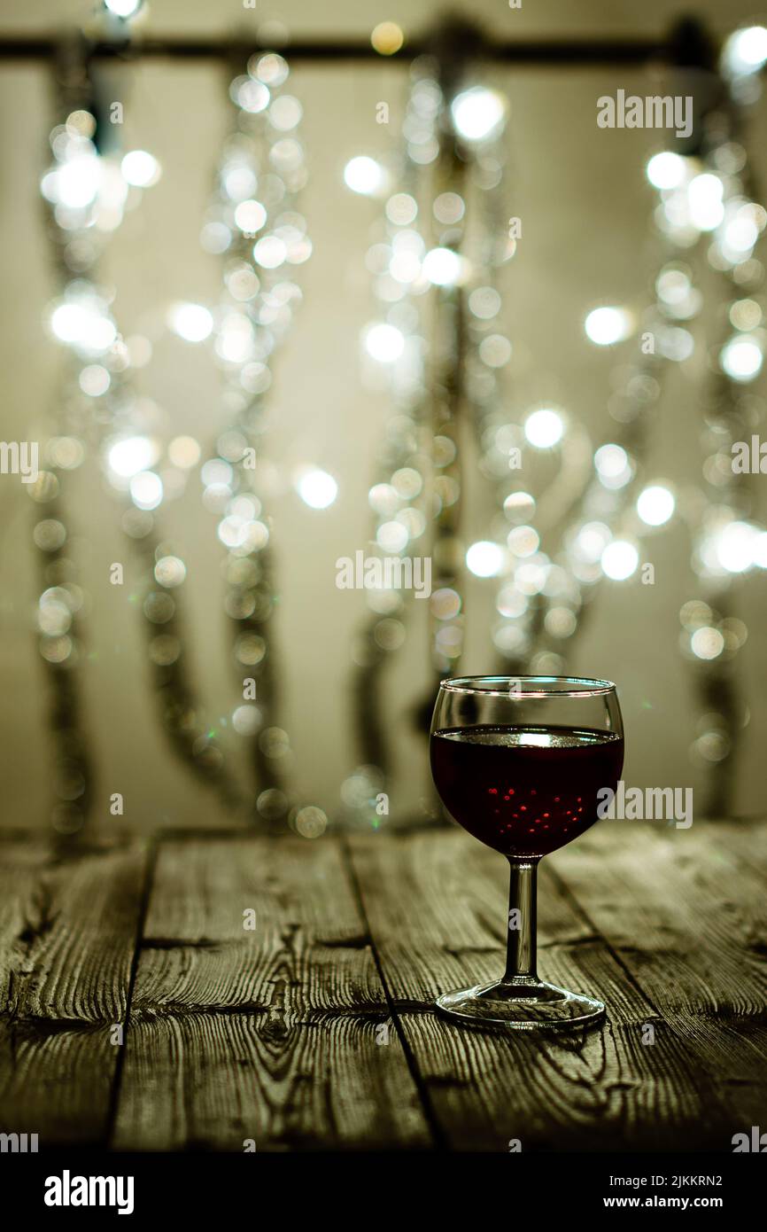 A closeup of a glass cup drink on a wooden surface on a blurry bokeh light background Stock Photo