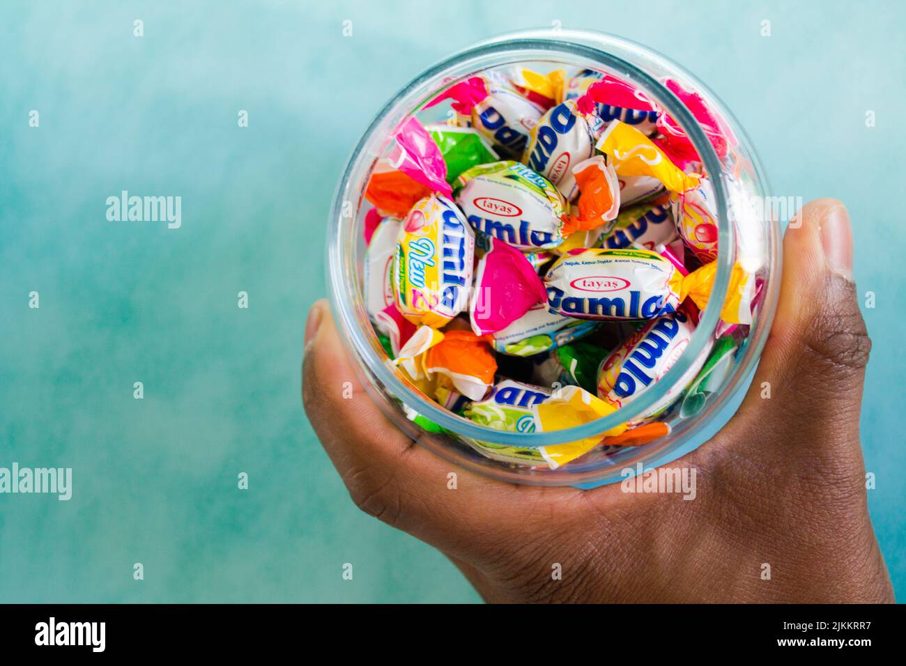 A top view of a man's hand holding a glass jar full of hard candy Stock