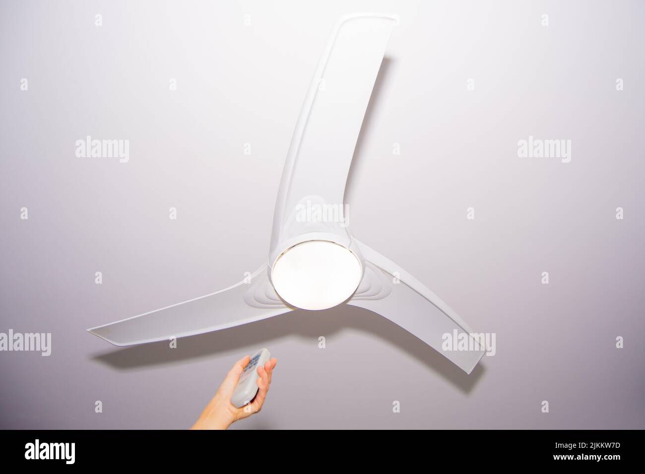 Hand turning on a ceiling fan with white background in a house Stock