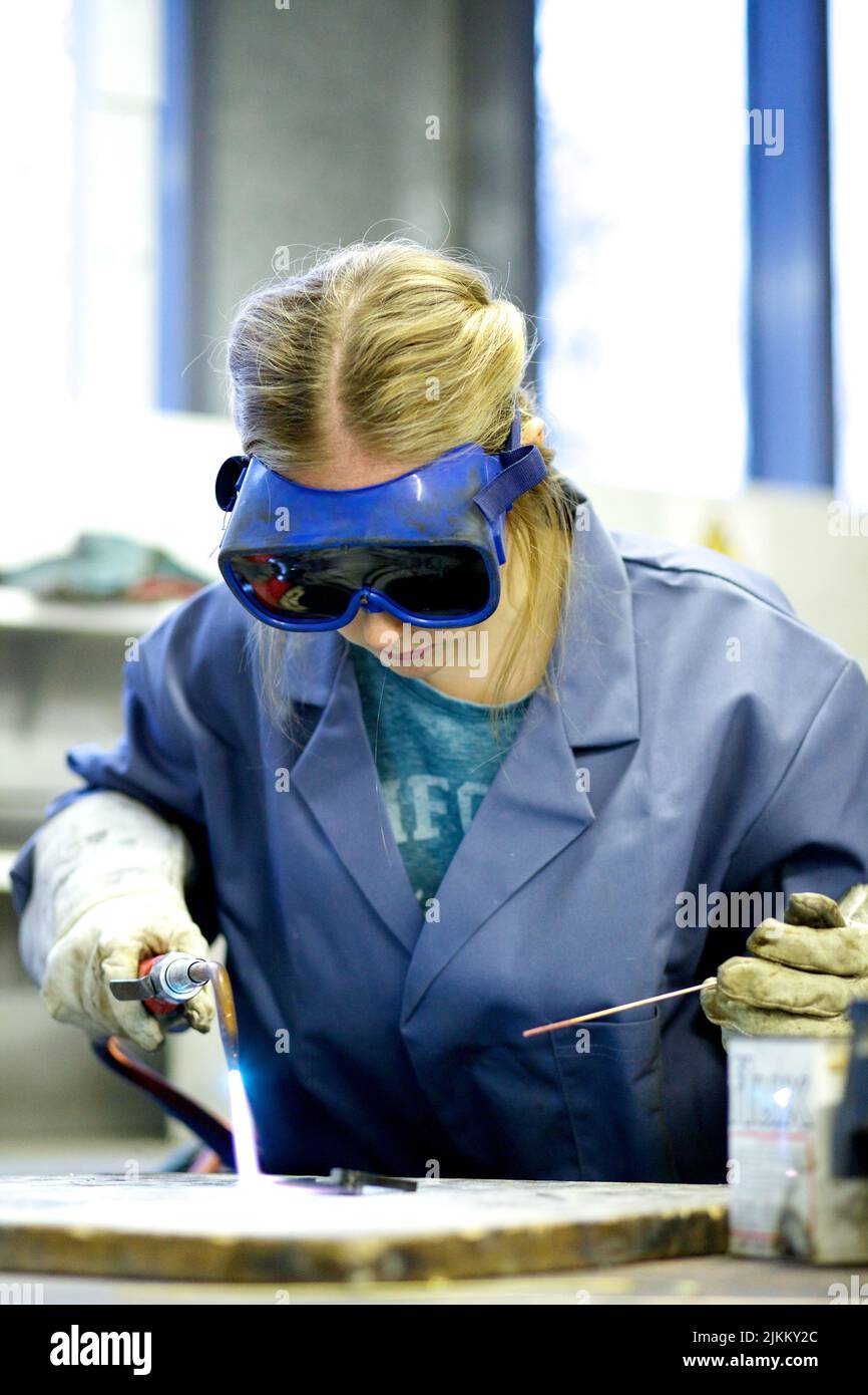 A female metal worker in goggles welding steel with a blow torch Stock Photo