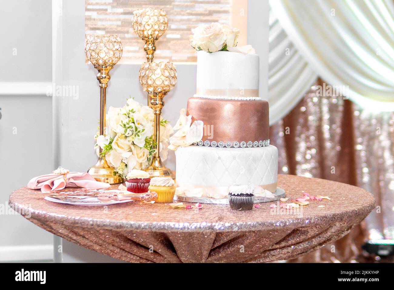 A beautiful wedding reception with pink wedding cake, candlesticks and flowers on the table Stock Photo