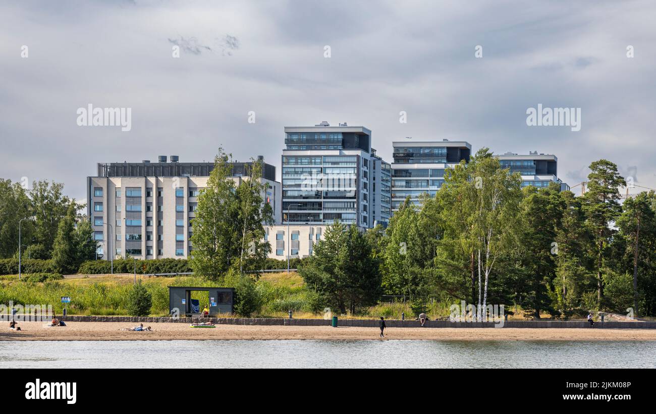 People on the beach in front of tall office buildings in Espoo, Finland Stock Photo